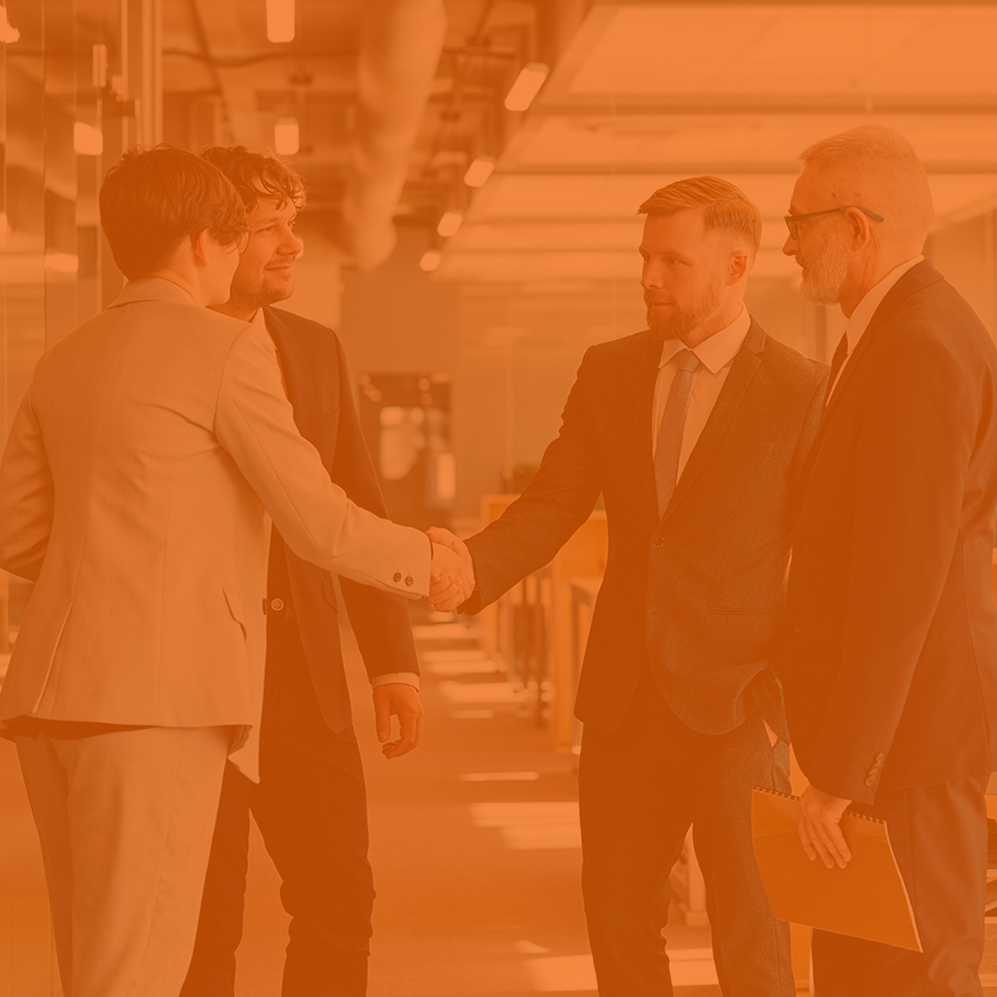 Three business professionals shaking hands in a modern office setting, symbolizing collaboration and agreement.