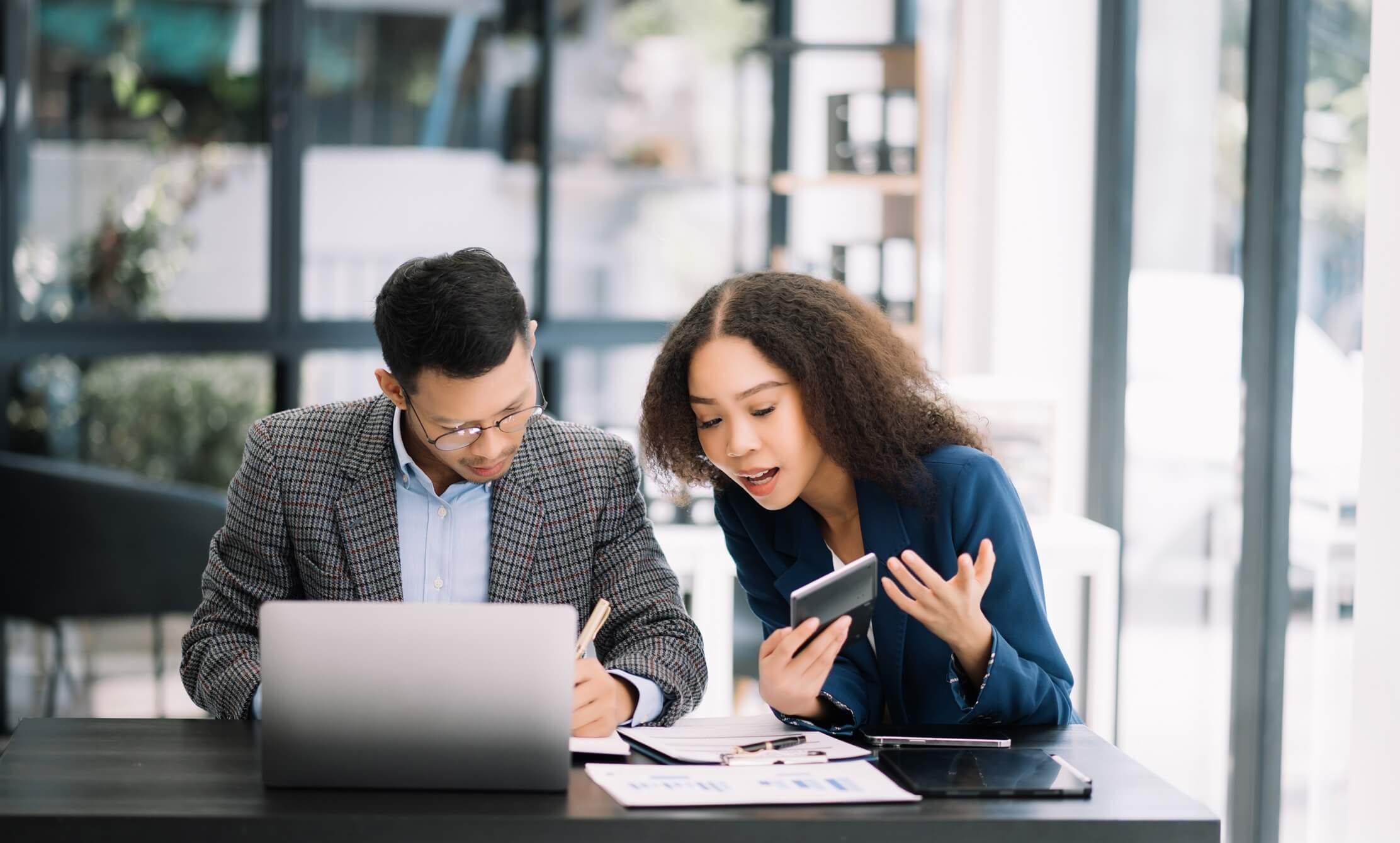 Two individuals examining a laptop while holding a credit card, engaged in a financial transaction or online shopping.