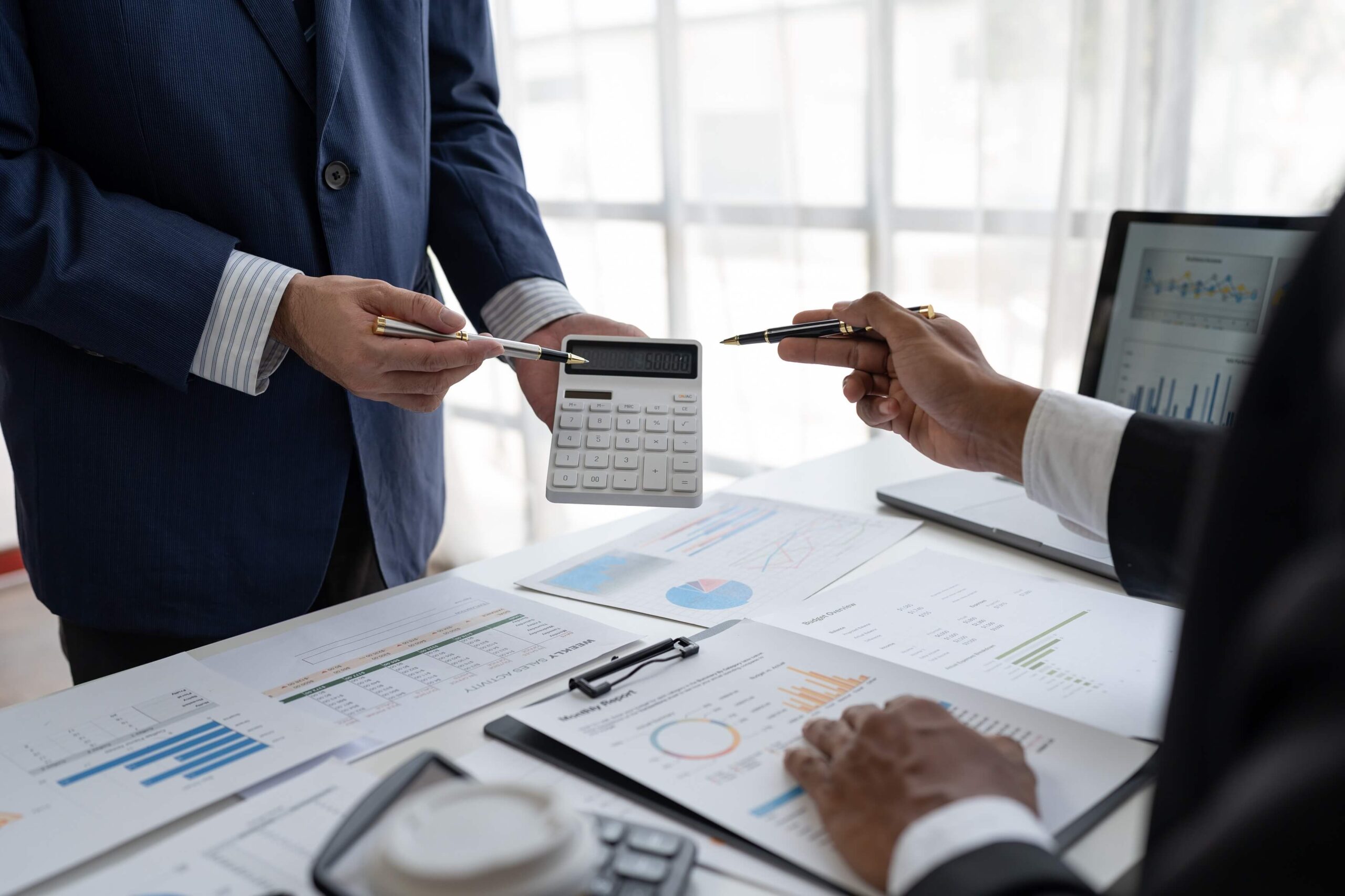 Two business professionals collaborating with a calculator and pen, symbolizing teamwork in financial planning.