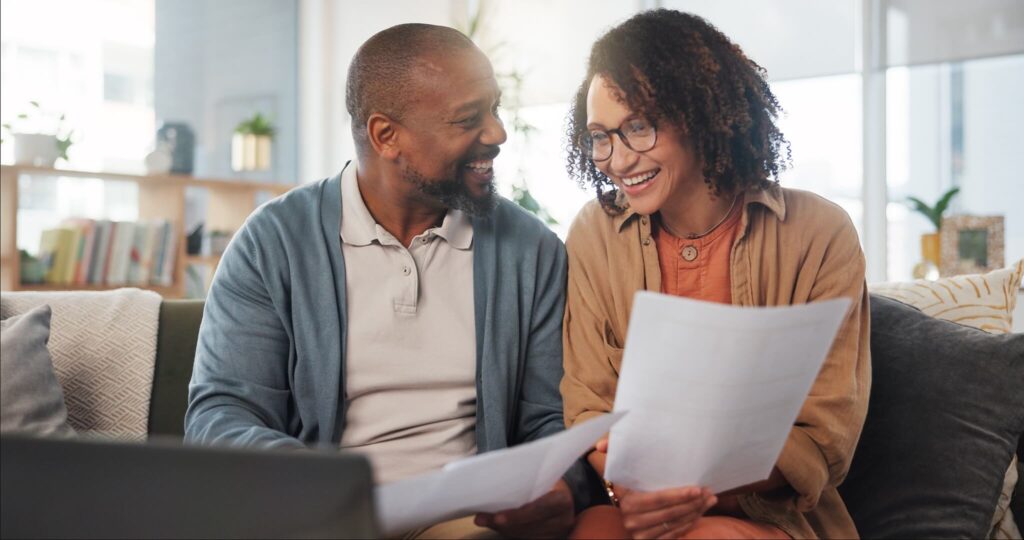 A happy couple reviewing their consolidated debt payment plan, feeling relieved about financial stability