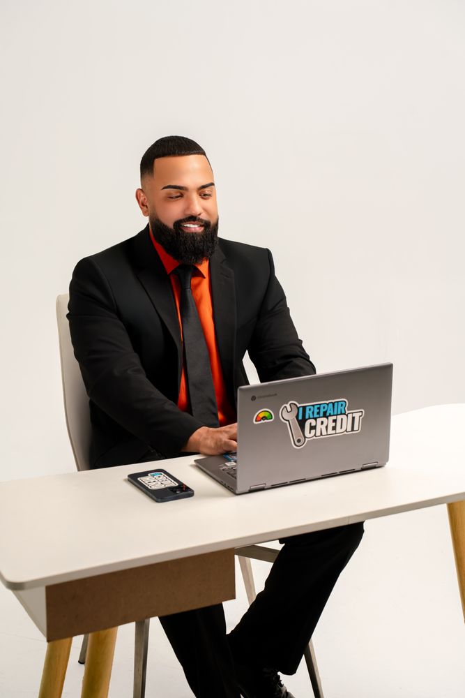 A man in a suit sits at a desk, focused on his laptop, conveying professionalism and dedication in a work environment.