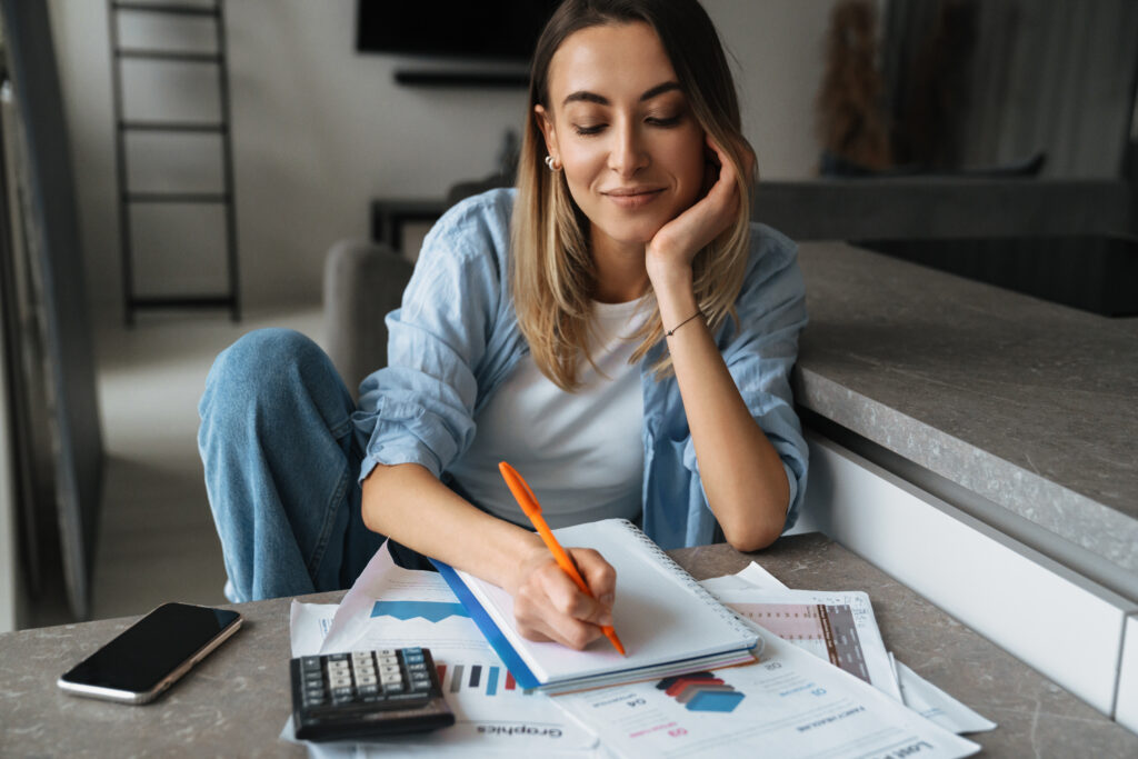 Stress-free woman reviewing her monthly budget after a successful debt settlement.